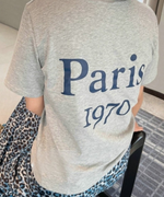 グレーの「Paris 1970」ロゴTシャツとブルーのレオパード柄ロングスカートを合わせたバックスタイル。