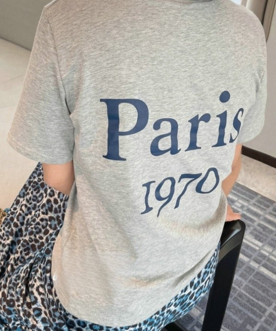 グレーの「Paris 1970」ロゴTシャツとブルーのレオパード柄ロングスカートを合わせたバックスタイル。