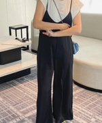 黒のキャミソールサロペットに白のパワーショルダーTシャツをインナーとして着用したが腕を組んだ女性の写真。