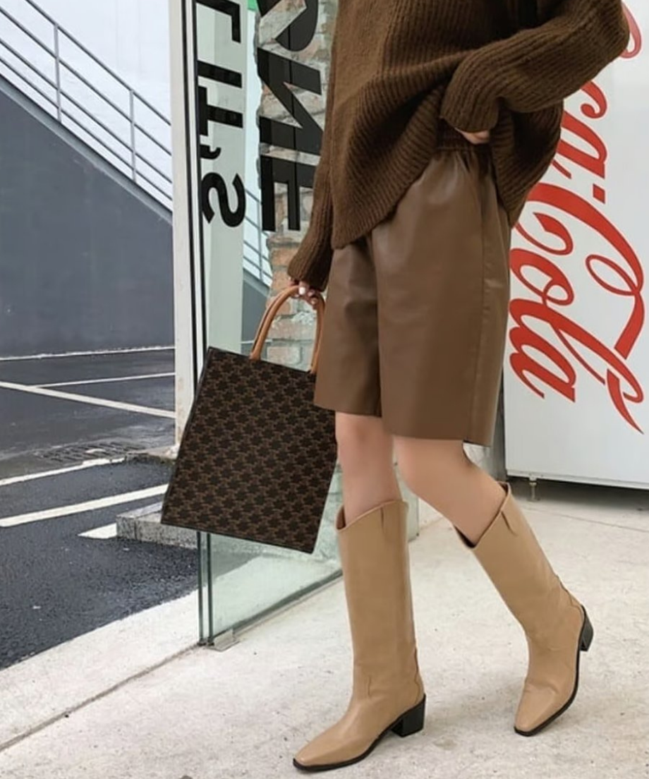 落ち着いたブラウンのレザーショーツに、同系色のニットをフロントインしたスタイリッシュな着こなし。