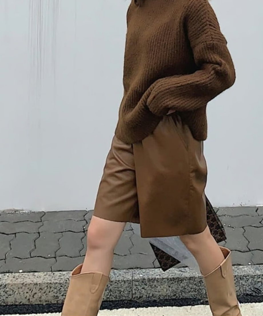 ブラウンのハイウエストレザーハーフパンツに、厚手のブラウンニットとベージュのロングブーツを合わせた秋のワントーンコーデ。