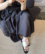 黒いマキシワンピースを着用した女性の足元に映えるオフホワイトのメタルサンダル