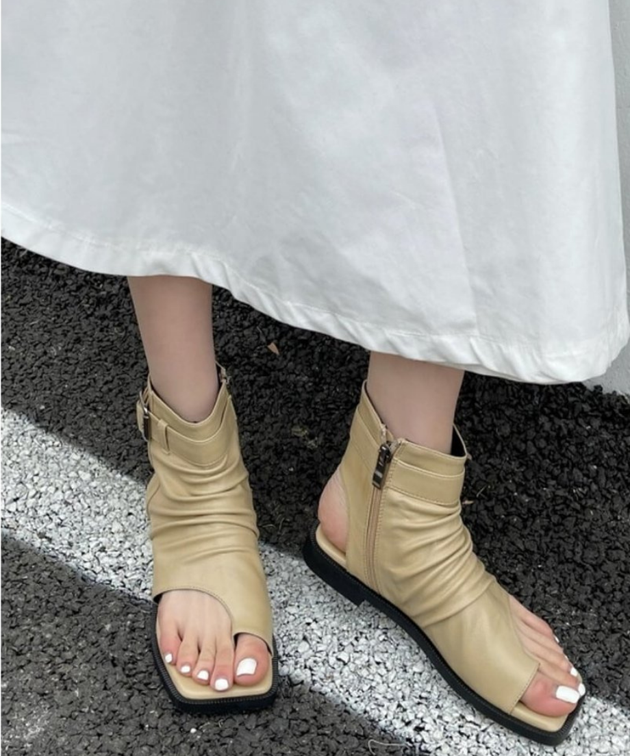 ベージュのブーツサンダルを履いて座り、足元を横から捉えたカット