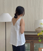 ホワイトのVネックブラウスの後ろ姿。背中の深いVカットとまとめ髪が特徴的