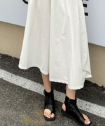 アスファルトの上で、黒のルーズなブーツサンダルを履いて立つ女性の正面カット