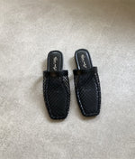 ブラックのスクエアトゥサンダルメッシュのスクエアトゥミュールが、グレーの床にペアで置かれている俯瞰画像。