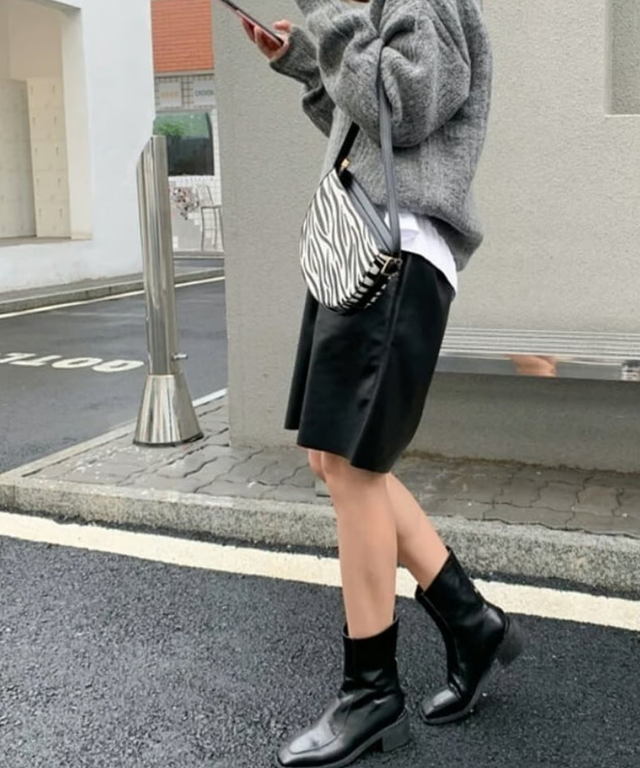 光沢のあるブラックのハーフパンツと、スクエアトゥの黒いサイドゴアブーツを履いたサイドスタイル。