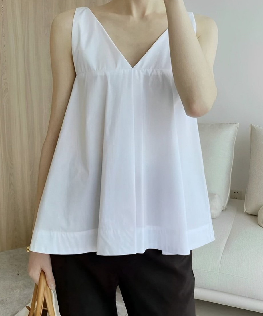 深いVネックと胸下のギャザーが特徴的な、白いノースリーブのフレアトップスの正面カット