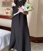 ブラックのバックオープンワンピースを着用し、白い百合の花束を持つ女性の全身