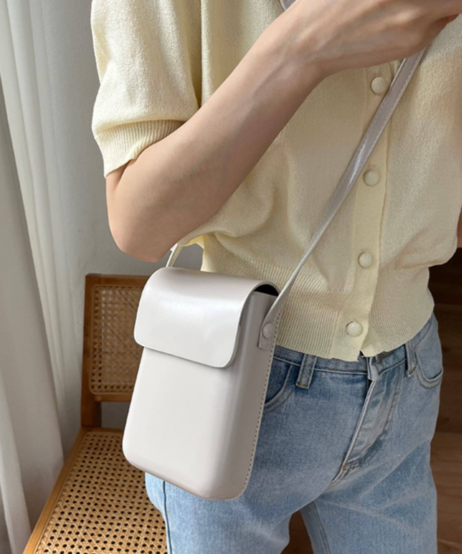 ホワイトフェイクレザーミニショルダーを斜めがけしている女性。