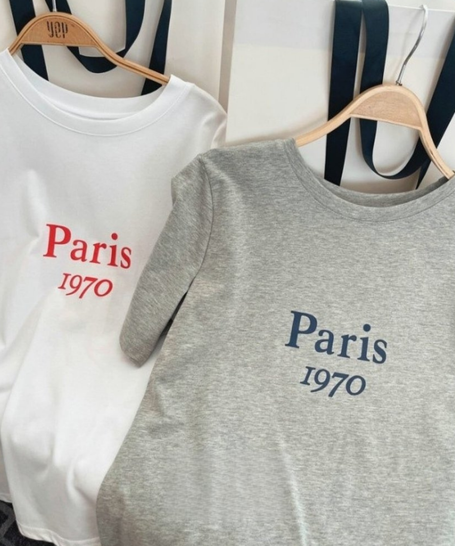 木製のハンガーに掛けられた、ホワイトとグレーの2色のロゴTシャツの比較画像
