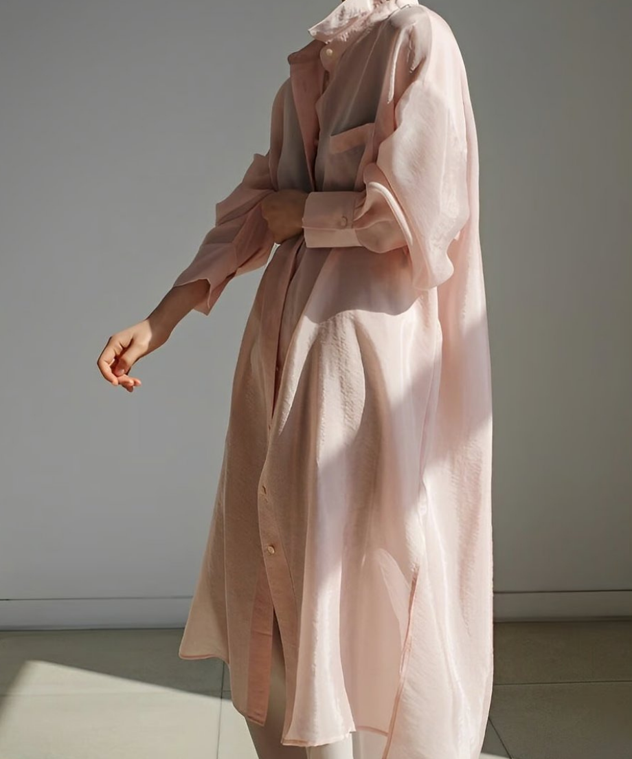 ピンクロングシャツのボタンを留め、パンツと合わせた落ち着いた雰囲気のコーディネート。