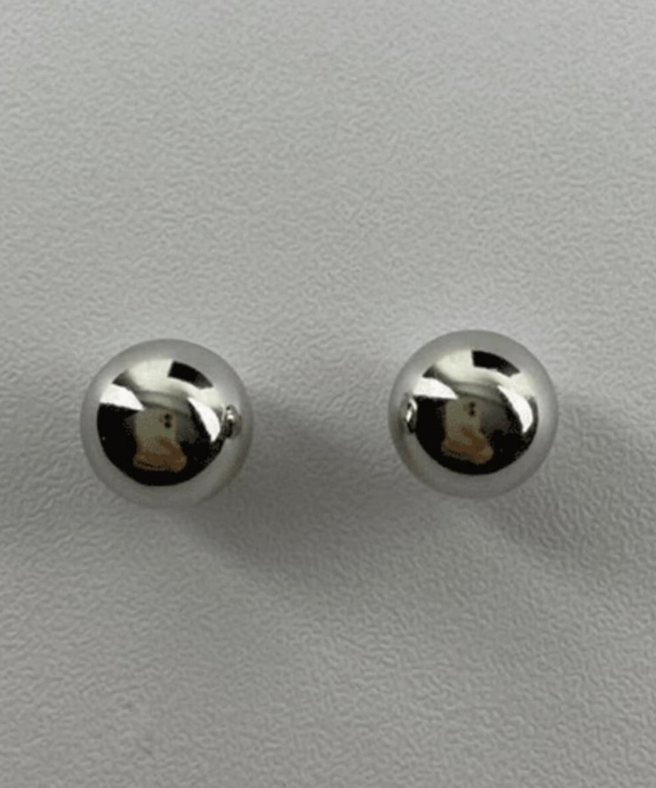 グレーの背景に並んだ、鏡面仕上げのシルバーボールピアス2つの俯瞰ショット。