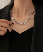 黒のジャケットを着用した女性の首元で、シルバーのUリンクチェーンネックレスが輝いている様子。