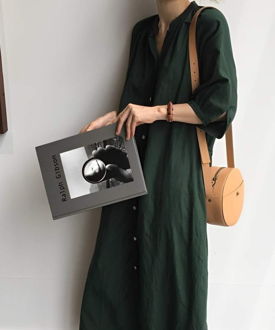 グリーンのVネックロングシャツワンピースを着た女性の横向きの写真。