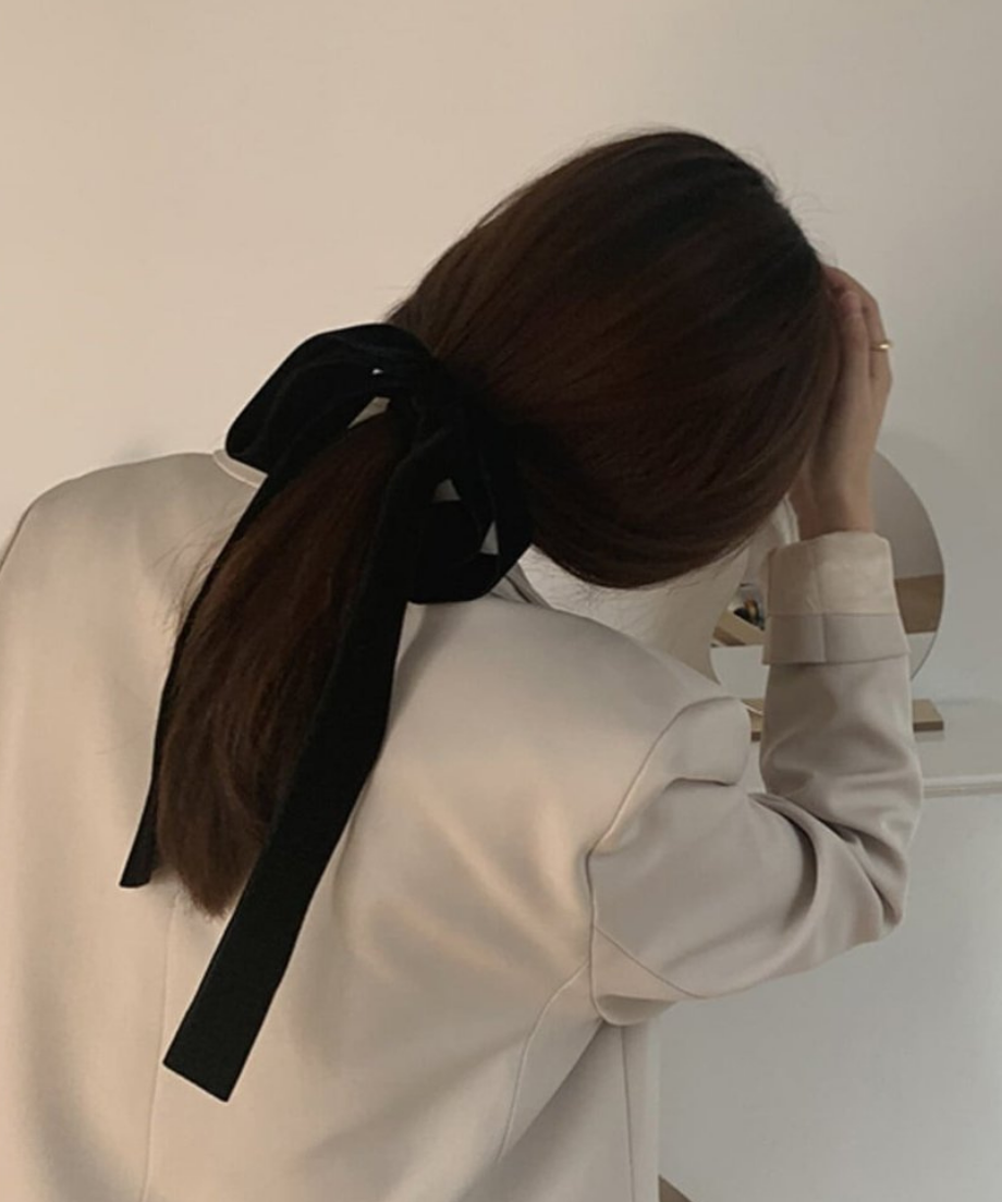 髪に手を添え、黒のベルベットリボンの柔らかな質感と立体感を見せる女性のバックスタイル。
