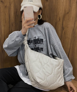 グレーのロゴ入りスウェットに白いキャップ、白いキルティングバッグを斜め掛けしてスマートフォンで鏡越しに自撮りをする女性。