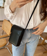ブラックフェイクレザーミニショルダーを斜めがけしている女性。
