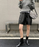 光沢のあるブラックのハーフパンツと、スクエアトゥの黒いサイドゴアブーツ。