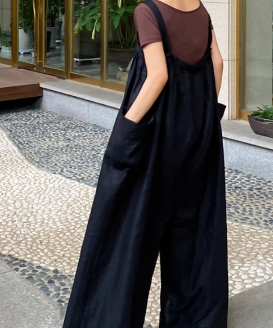 黒のリネンワイドサロペットにブラウンのシアーなインナーを合わせた女性が、後ろを向いた写真。