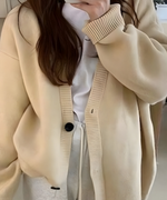 オフホワイトのオーバーサイズカーディガンを白いTシャツの女性の上半身。