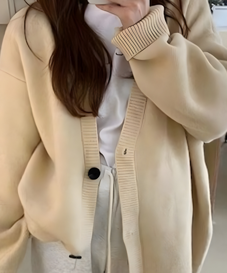 オフホワイトのオーバーサイズカーディガンを白いTシャツの女性の上半身。