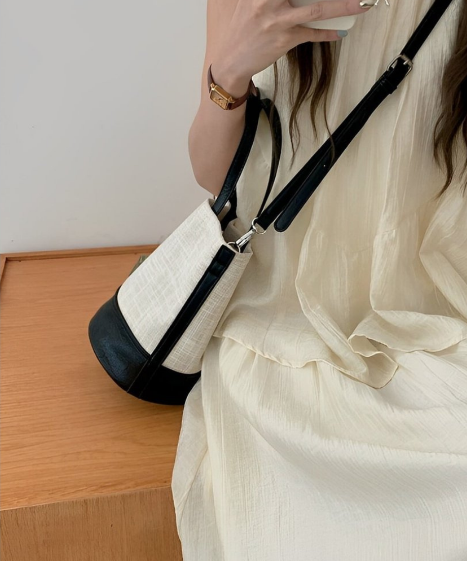 バッグを肩にかけにスマートフォンを操作する女性。