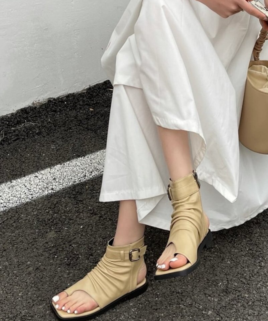 白いロングスカートとベージュのシャーリングブーツサンダルを合わせた女性。