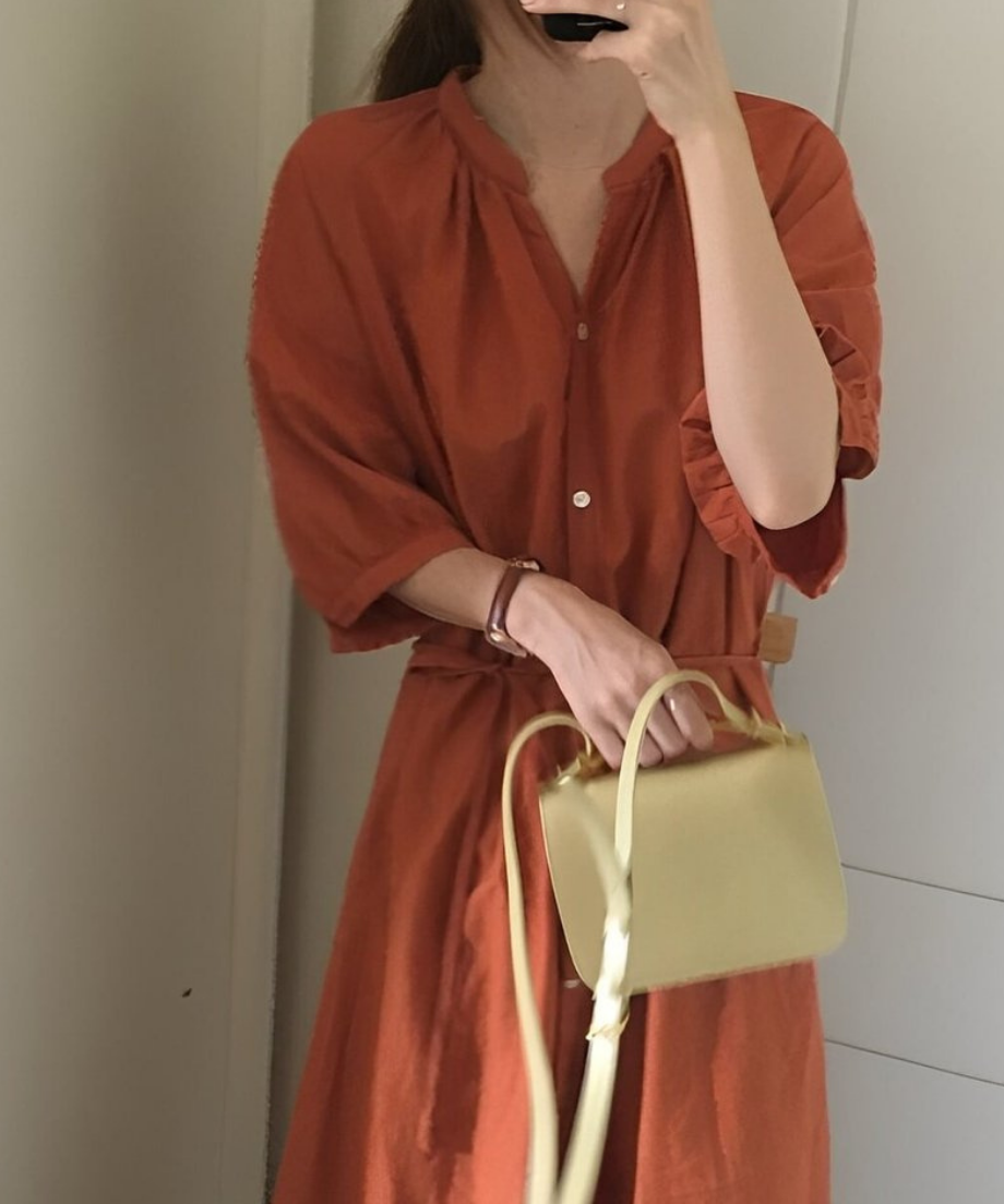 オレンジブラウンのVネックロングシャツワンピースを着た女性が自撮りしている。