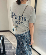 グレーの「Paris 1970」ロゴTシャツとブルーのレオパード柄ロングスカートを合わせたバックスタイル。