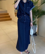 濃紺のデニムセットアップを着用した女性の全身像。黒の細いストラップサンダルを履いている。