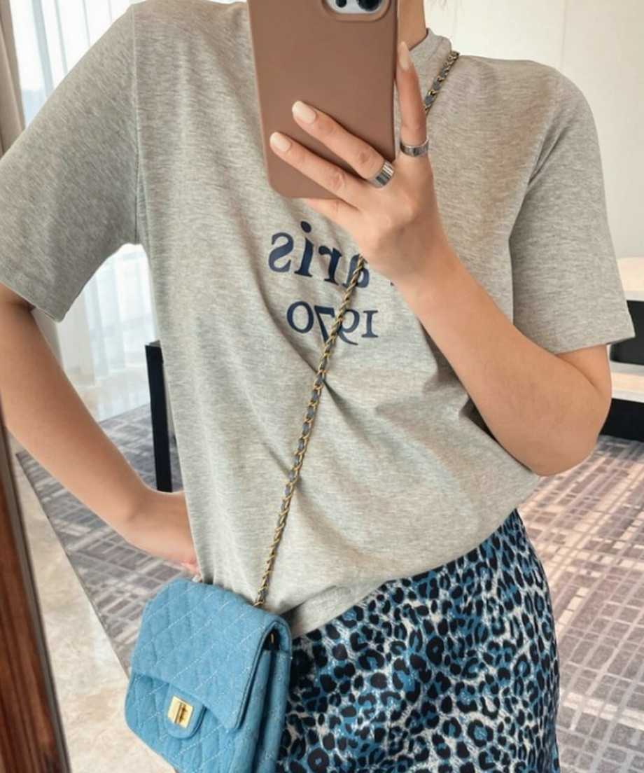 グレーのTシャツにブルーのチェーンバッグを斜めがけした、こなれ感のあるスタイリング。