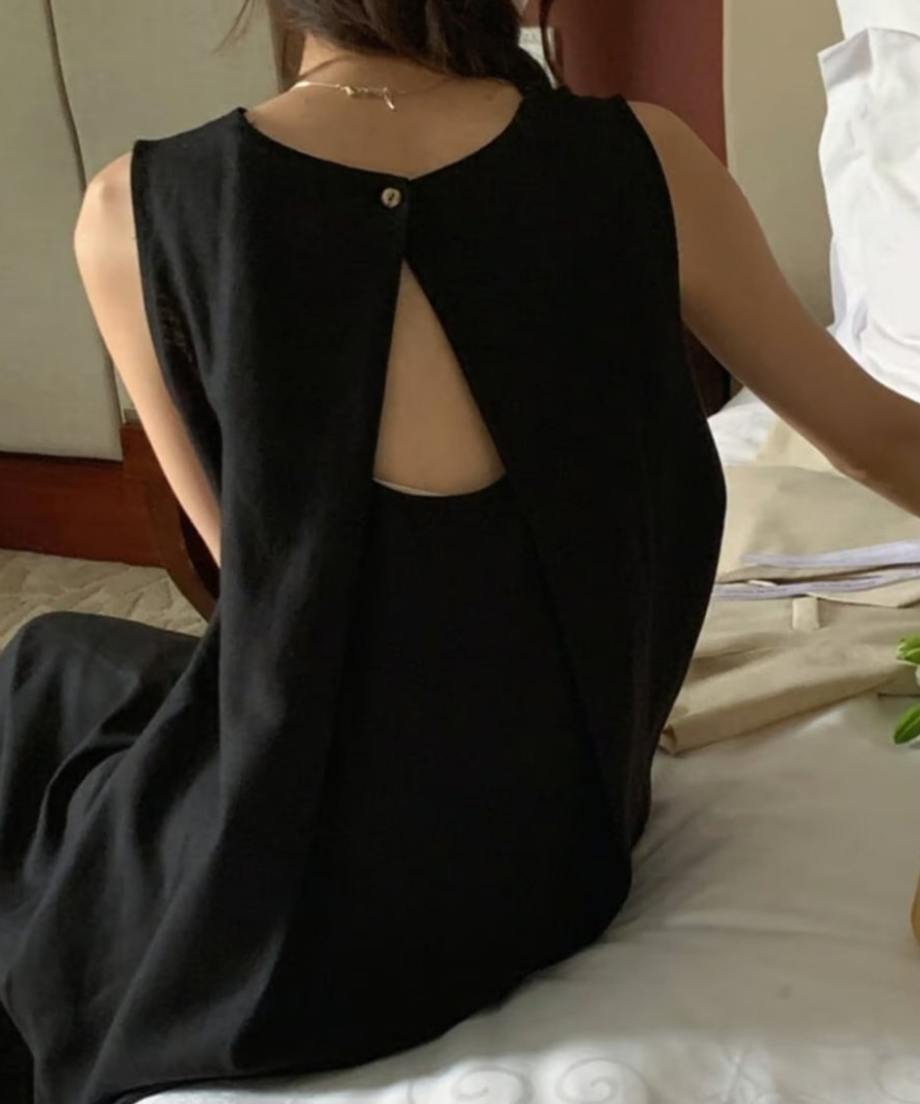 背面のV字カッティングとボタンが特徴的なブラックのワンピースを着た女性の背中のアップ。
