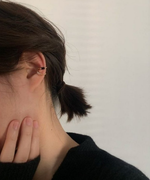 黒いトップスを着用した女性の耳元を飾る、シックでモダンな印象のイヤーカフスタイリング。