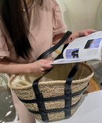ピンクのワンピースを着用した女性が、開口部の巾着裏地から荷物を確認している様子。