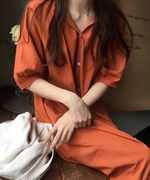 オレンジブラウンのVネックロングシャツワンピースを着た女性が座っている写真。