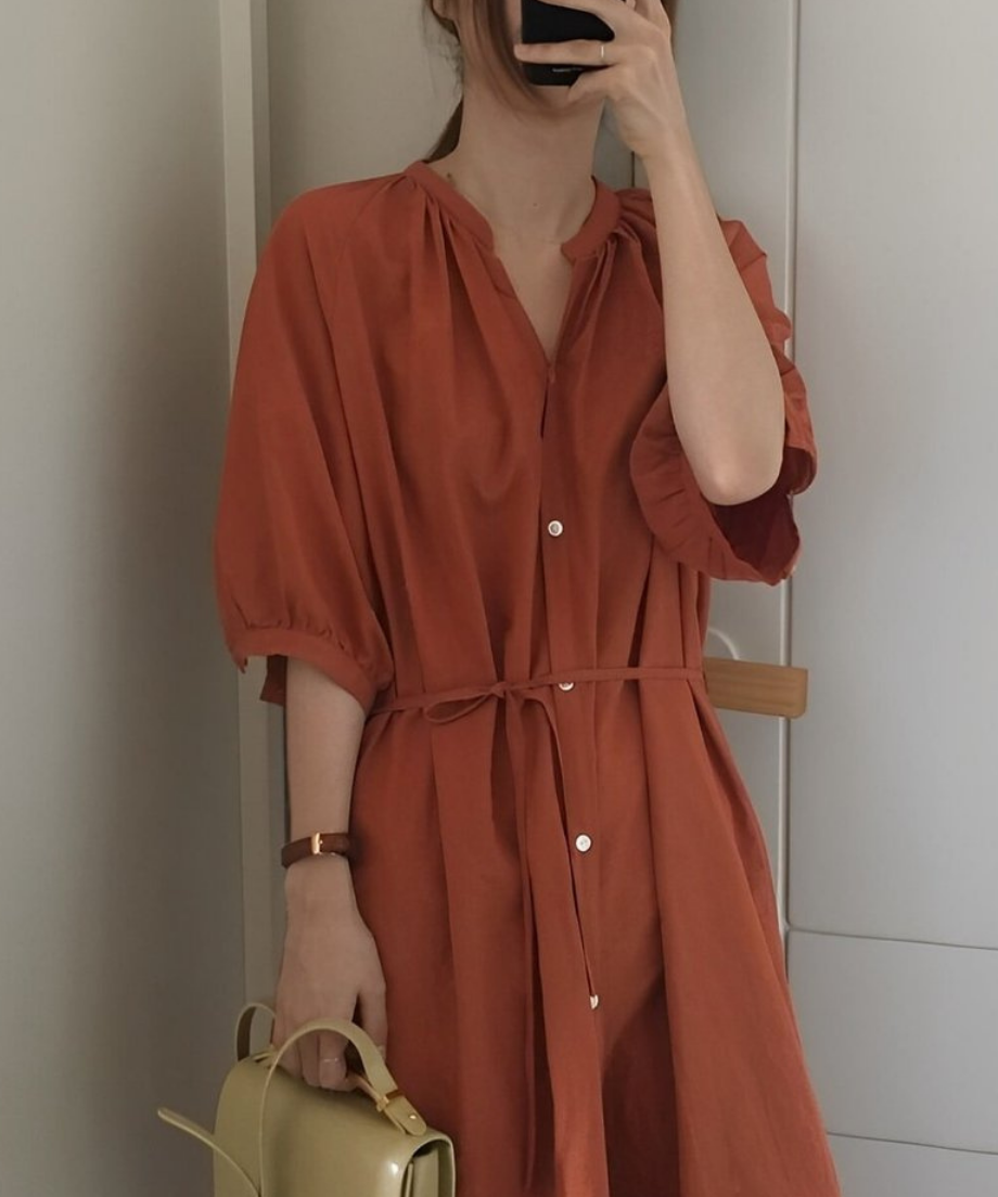 オレンジブラウンのVネックロングシャツワンピースを着た女性の上半身。