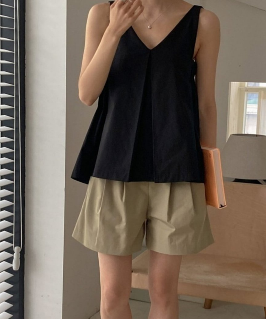 ブラックのVネックブラウスにベージュのショートパンツを合わせた女性の正面カット。