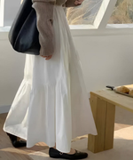 ホワイトティアード切り替えマキシスカートを履いた女性の側面。