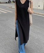 黒のロングチュニックにデニム、サンダルを合わせた、街角に立つ女性の全身スタイリング。