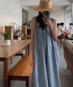 水色のノースリーブワンピースを着用した女性。