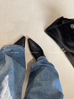 黒いバッグと白い床に、水色のデニムパンツとブラックのポインテッドトゥミュールを着用した足元が写っている俯瞰写真。
