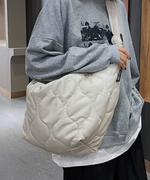 体にフィットするようなフォルムのホワイトキルティングバッグを斜め掛けて立つ女性。