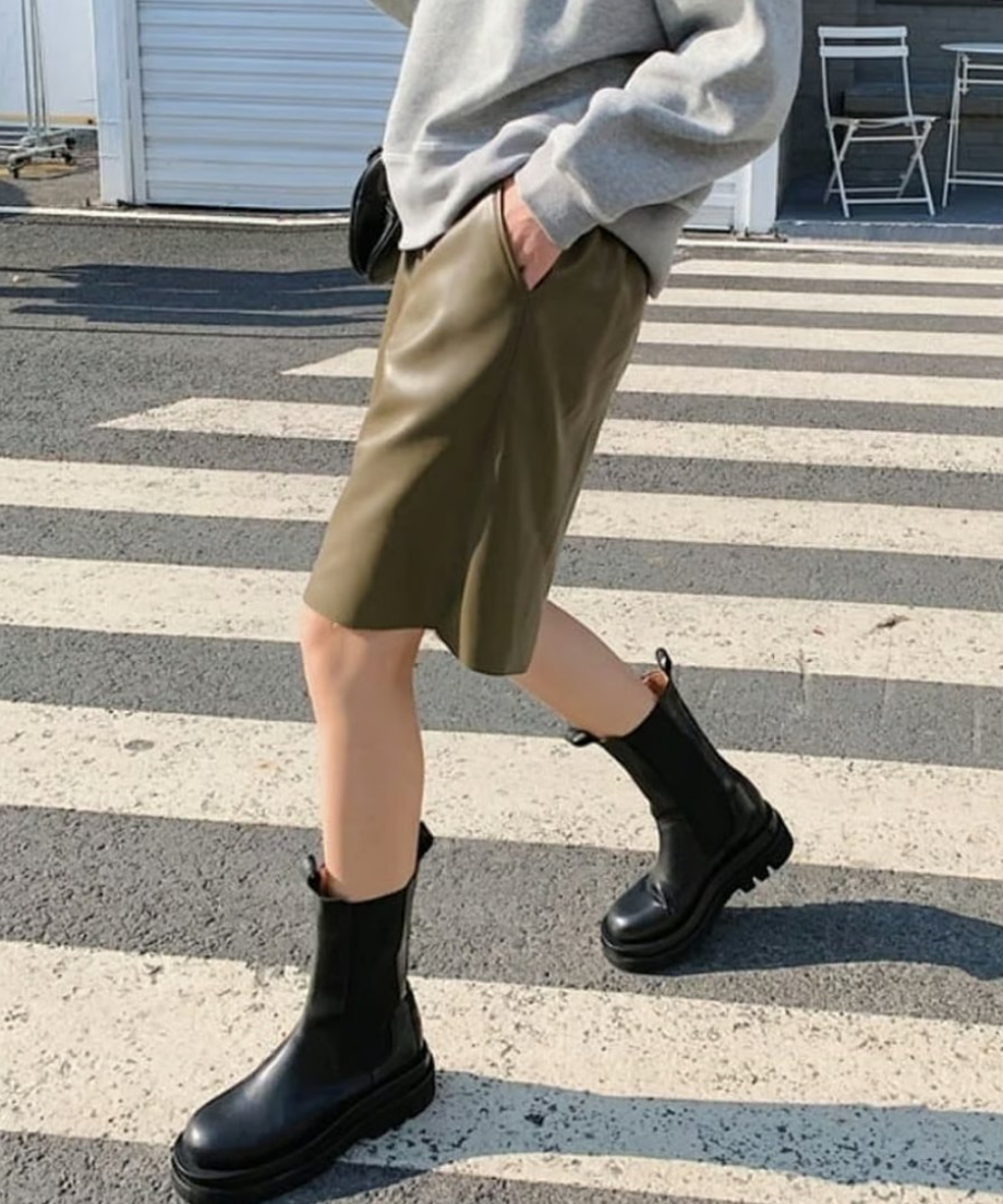 オリーブのハーフパンツに黒の厚底サイドゴアブーツを合わせ、横断歩道を歩くアクティブなデイリールック。