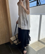 光が差し込む室内でカゴバッグを持ち、黒のサンダルを履いて歩く女性の足元