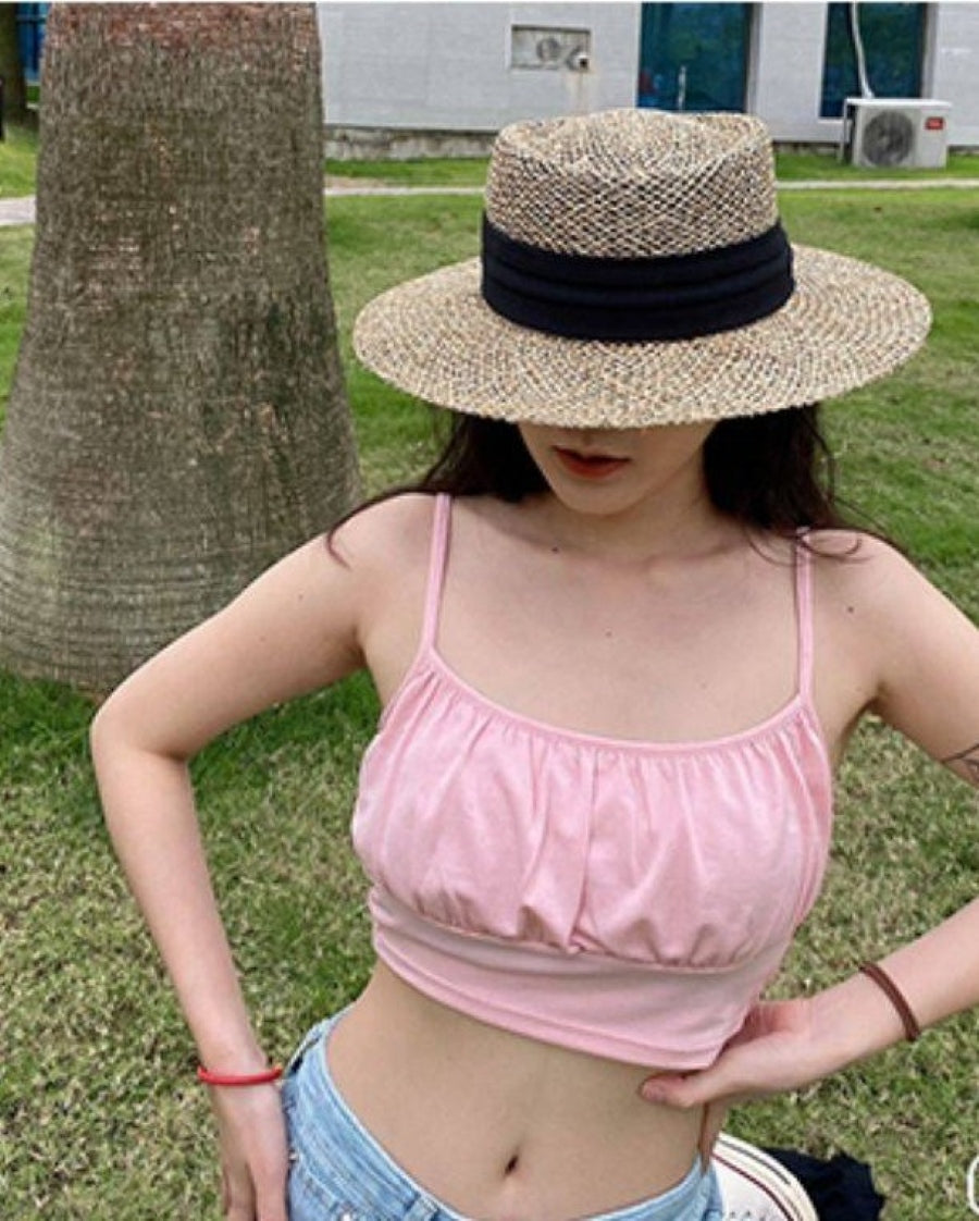 屋外でブラックのストローハットを着用した女性の全身に近い写真。リゾート風のスタイリングイメージ。