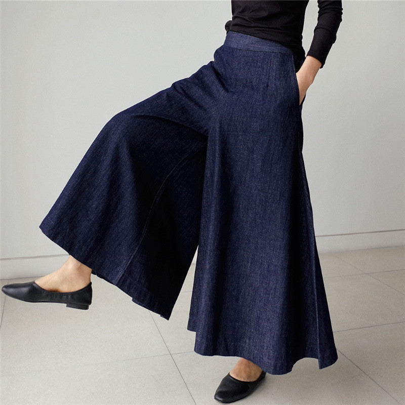 ブルーのルーズワイドレッグデニムパンツを履いたモデル。シンプルな黒いトップスと合わせている。