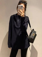 ブラックのオーバーサイズフーディーを着用し、サングラスを頭に乗せて鏡越しに撮影している女性。フロントにはジップとカンガルーポケットのディテールが見える。