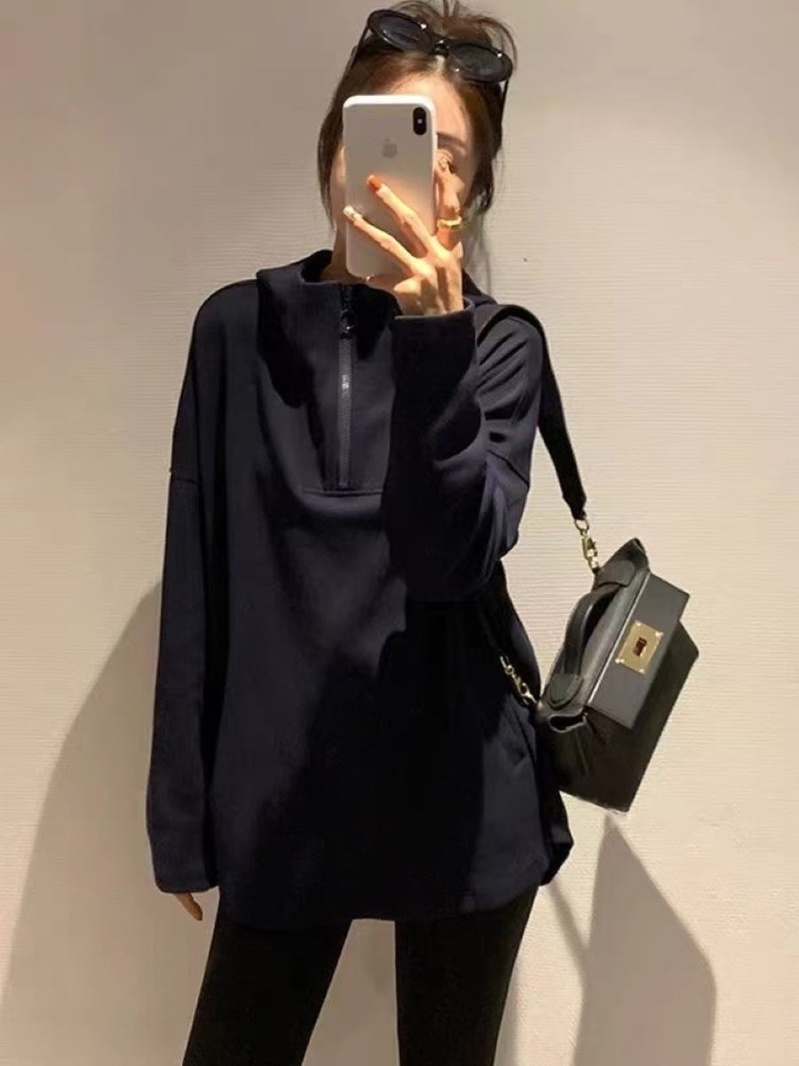 ブラックのオーバーサイズフーディーを着用し、サングラスを頭に乗せて鏡越しに撮影している女性。フロントにはジップとカンガルーポケットのディテールが見える。