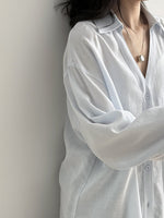 ライトブルーのVネックブラウスを着た女性。涼しげで爽やかな印象。